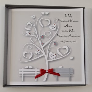 Könnte beinhalten: Eine graue und weiße Karte mit einem weißen Papier-Ausschnittbaum mit roten Herzen und einem roten Band auf einer Bank. Die Karte sagt "To My Wonderful Husband Adrian On Our 10th Wedding Anniversary 4th February 2021".