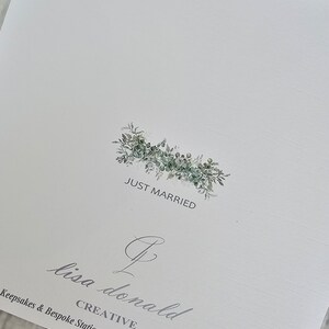 May include: A white card with a green leafy floral wreath with the text "Just Married" in the center. Below the wreath is a cursive signature that reads "Lisa Donald Creative" with the website address "https://lisadonaldcreative.co.uk".