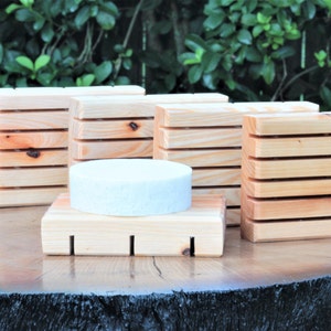 May include: Five wooden soap dishes with a white soap bar on top of one of the dishes. The soap dishes are made of natural wood and have a rustic look.