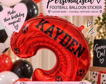 Puede incluir: Un globo de aluminio rojo con forma de número, decorado con pegatinas de vinilo negro de balones de fútbol y el nombre KAYDEN en letras negras. La imagen incluye textos superpuestos que dicen Pegatina personalizada para globo de fútbol y Solo pegatinas de vinilo.