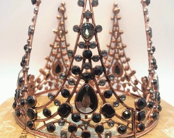 May include: A copper-toned crown with black and clear rhinestones. The crown has a pointed design with three peaks.