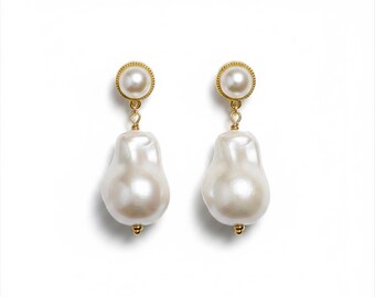 May include: A pair of drop earrings featuring a round white pearl stud with a gold-toned textured border, connected by a small gold link to a large, irregular, teardrop-shaped white baroque pearl that hangs vertically from the stud.