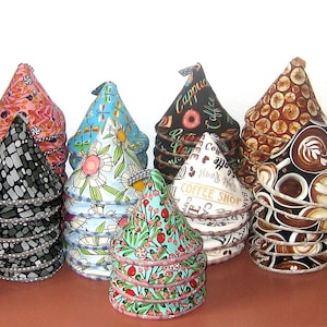 May include: A collection of colorful fabric cone-shaped pot holders with various patterns, including floral, geometric, and coffee-themed designs. The pot holders are stacked in a pyramid shape.