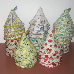 Könnte beinhalten: Ein Set aus sechs Stoffkegeln mit floralen und geometrischen Mustern. Die Ornamente sind pyramidenförmig gestapelt und in verschiedenen Farben gehalten, darunter Rot, Weiß, Blau, Grün und Gelb.