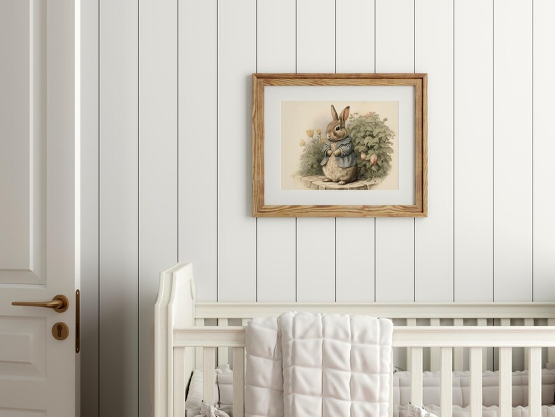Peut inclure: Une illustration encadr&eacute;e d'un lapin brun portant une veste bleue et tenant une fleur. Le lapin se tient dans un jardin avec des feuilles vertes et des fleurs roses. Le cadre est en bois et a une finition brun clair.