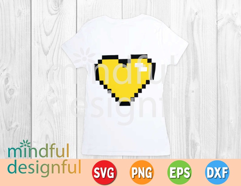 May include: White t-shirt featuring a pixelated yellow heart with black outlines. The shirt has a crew neck and short sleeves. The words "mindful designful" are printed at the bottom left. The image also includes SVG, PNG, EPS, and DXF icons.
