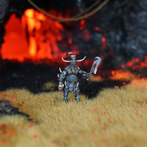 May include: A miniature figure of a warrior with horns, wearing armour and holding a sword. The figure is standing in a field of long grass with a fiery cave in the background.
