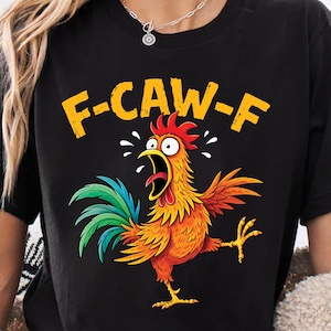 May include: Black t-shirt with a cartoon rooster design and the text "F-CAW-F" in yellow. The rooster is depicted with an open beak, orange, red, yellow, and green feathers, and one leg raised. The design is centered.