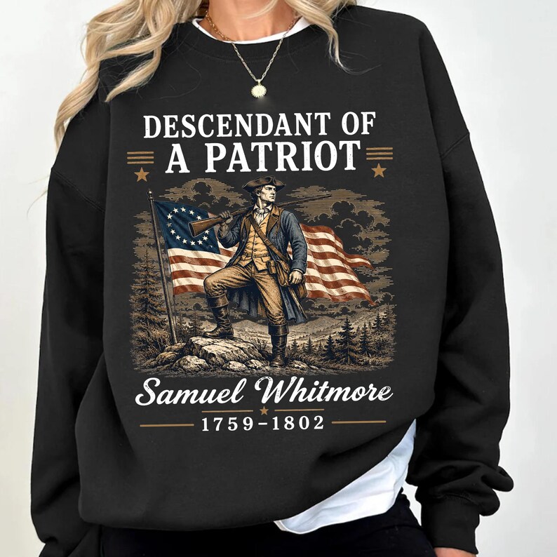 May include: Black sweatshirt with a graphic of a colonial man holding a rifle in front of an American flag. Text reads "Descendant of a Patriot" above "Samuel Whitmore 1759-1802".