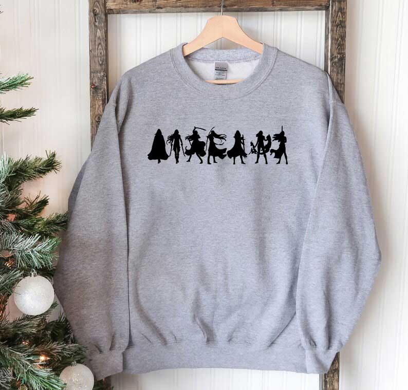 May include: A gray sweatshirt with a black silhouette of a group of women in various poses. The women are wearing different outfits and accessories, including capes, swords, and hats.