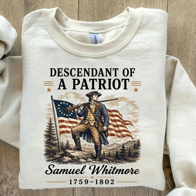 May include: Cream-colored sweatshirt featuring a graphic of a man in colonial attire holding a rifle, with an American flag in the background. Text reads "Descendant of a Patriot" and "Samuel Whitmore 1759-1802".