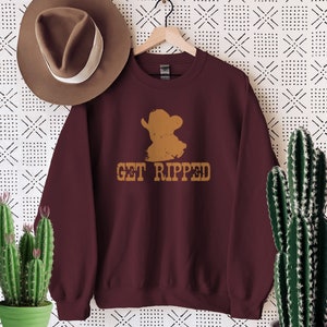 May include: Burgundy sweatshirt with a distressed brown cowboy silhouette and the text "GET RIPPED" in brown.