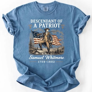 May include: Blue t-shirt featuring a graphic of a man holding a rifle in front of an American flag. The text reads "Descendant of a Patriot" and "Samuel Whitmore 1759-1802".