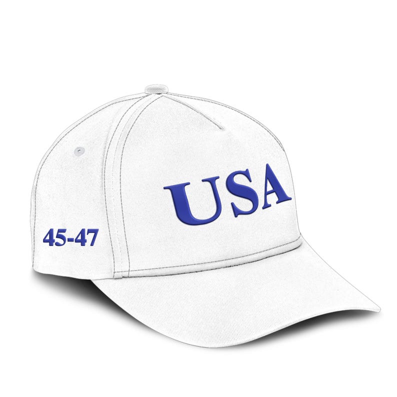 Puede incluir: Gorra de b&eacute;isbol blanca con la palabra "USA" en azul y los n&uacute;meros "45-47" en el lateral. La gorra tiene una visera curva y un bot&oacute;n en la parte superior. Las costuras son visibles.