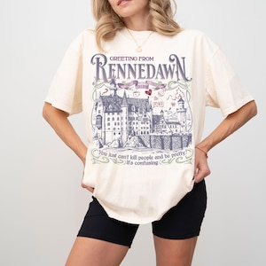 May include: Off-white t-shirt with a graphic that says "Greeting From Rennedawn." The graphic shows a detailed castle illustration and the text "You just can't kill people and be pretty. It's confusing."