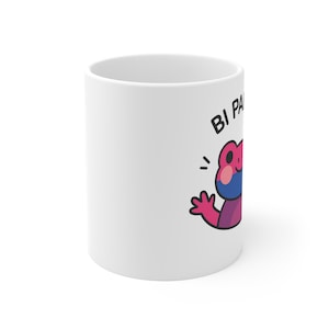 Puede incluir: Taza de cerámica blanca con una rana de dibujos animados en rosa, azul y morado, y el texto "BI PA" en negro. La rana está saludando. La taza es de tamaño estándar.