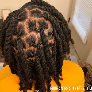 Pu&ograve; includere: Primo piano di una persona con dreadlocks acconciate a forma di motivo. Le dreadlocks sono nere e sono acconciate a forma di griglia sulla parte superiore della testa. Le dreadlocks sono lunghe e scendono lungo la schiena della persona.