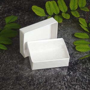 Piccola confezione regalo bianca con inserto in ecofibra bianca. Ideale per la presentazione di gioielli e piccoli articoli da regalo. Nastro opzionale e cartellino regalo.