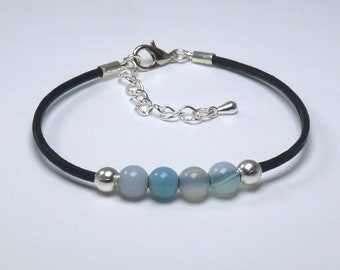 Bracelet pierre précieuse Bleu Onyx Agate. Quatre pierres semi-précieuses rondes et deux perles plaquées argent sur un cordon en cuir noir.