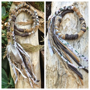 May include: A brown and white braided hair wrap with a feather and fabric tassels. The wrap is made of leather and fabric and has a rustic, bohemian style.