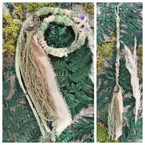 May include: A handcrafted headpiece and wand featuring a bohemian aesthetic. The headpiece has a circular design with green, beige, and pink accents, adorned with crystals and flowers. The wand is wrapped in similar materials, with a crystal and tassel.
