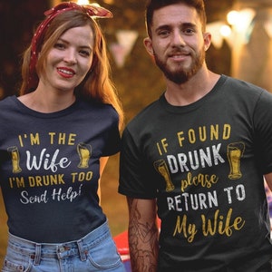 May include: A couple wearing matching navy blue and black t-shirts with a beer-themed design. The woman's shirt says "I'm the Wife I'm Drunk Too Send Help!" and the man's shirt says "If Found Drunk Please Return To My Wife".