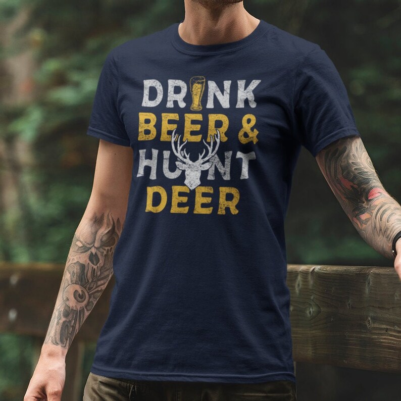 May include: A navy blue t-shirt with a distressed yellow graphic that reads "Drink Beer & Hunt Deer". The graphic also includes a white silhouette of a deer head with antlers.