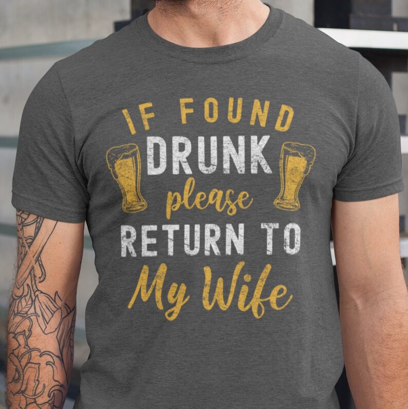 May include: A gray t-shirt with a distressed white graphic that reads "If found drunk please return to my wife". The graphic includes two beer mugs.