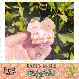 May include: A pink and orange badge reel with two cartoon babies and the text "Pumpkin Patch".