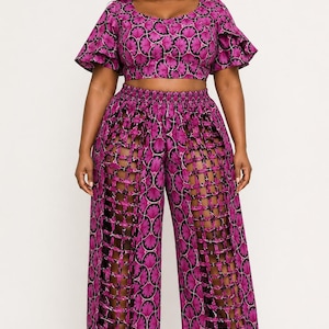 May include: A two-piece set featuring a cropped top with short flutter sleeves and wide-leg pants. Both pieces are made from a vibrant magenta and black fabric with a repeating fan-like pattern. The pants feature vertical lattice cutouts.