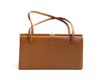 May include: A brown ostrich leather handbag with a gold clasp and a double strap.