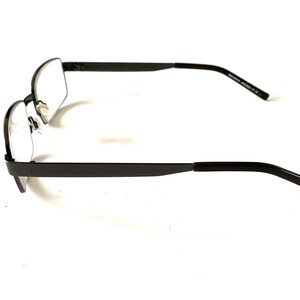 May include: A pair of rectangular-framed eyeglasses with a dark gray metal finish. The glasses have clear lenses and a minimalist design, suitable for everyday wear. The temples are straight and extend to the ear pieces.