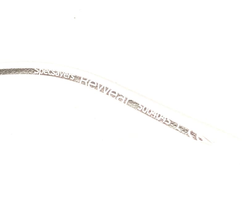 May include: Close-up of a white cable with the text "Specsavers Rewear 5004032347" printed on it.