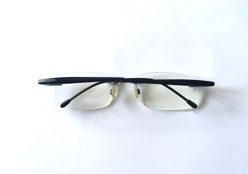 May include: Black rimless glasses with a thin metal frame and clear lenses.