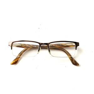 May include: Brown tortoiseshell eyeglasses with a metal frame and clear lenses. The brand name "Ray-Ban" is visible on the arms.