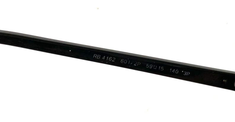 May include: Close-up of a black eyeglass arm with the text "RB 4162 601/2P 59口15 140 *3P". The arm is sleek and rectangular, with the text in white. The glasses are likely for vision correction or sun protection.