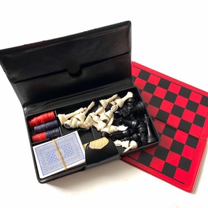 May include: A black leather case with a chessboard, chess pieces, and a deck of cards. The case is open and the chessboard is visible. The chess pieces are white and black.