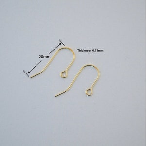May include: Two gold-coloured earring hooks. The hooks are 20mm long and 0.71mm thick. The hooks have a curved design with a loop at the top for attaching to an earring. The hooks are displayed against a light background.