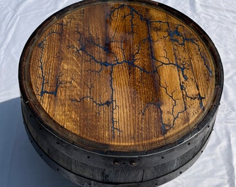 May include: A wooden barrel table top with a dark blue epoxy resin finish. The resin has a crackled effect, resembling lightning strikes. The table top is mounted on a black metal base.
