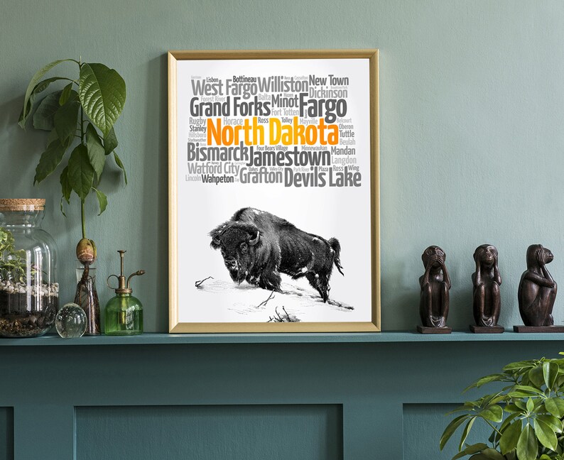 May include: A black and white illustration of a buffalo with a word cloud of cities in North Dakota. The word cloud is in orange and gray text on a white background. The cities listed are: Dickinson, West Fargo, Williston, New Town, Grand Forks, Minot, Fargo, Stanley, Rugby, Horace, Fort Totten, Devils Lake, Bismarck, Jamestown, Mandan, Langdon, Wahpeton, Grafton, and Watford City.