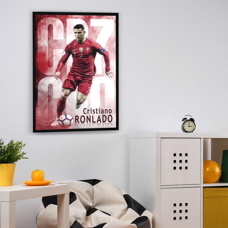 Puede incluir: Un p&oacute;ster enmarcado con un jugador de f&uacute;tbol con una camiseta roja con el n&uacute;mero 7 en la espalda. El jugador est&aacute; regateando un bal&oacute;n de f&uacute;tbol. El p&oacute;ster tiene un fondo rojo y blanco con el texto "Cristiano Ronaldo" en la parte inferior.