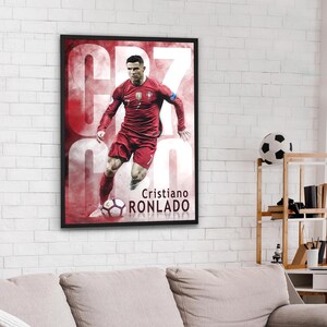 Puede incluir: Un p&oacute;ster con un jugador de f&uacute;tbol con una camiseta roja con el n&uacute;mero 7 en la parte delantera. El jugador est&aacute; regateando un bal&oacute;n de f&uacute;tbol. El p&oacute;ster tiene un fondo rojo y blanco con el texto "Cristiano Ronaldo" en la parte inferior.