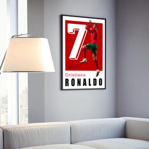 May include: A red and white poster with a photo of Cristiano Ronaldo celebrating a goal. The poster has the number 7 in white and the text "Cristiano Ronaldo" in black.