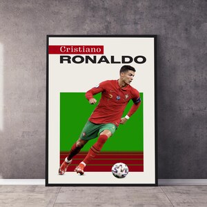 May include: A poster featuring Cristiano Ronaldo in a red and green soccer uniform, dribbling a soccer ball on a green field. The poster has the text "Cristiano RONALDO" in black and red.