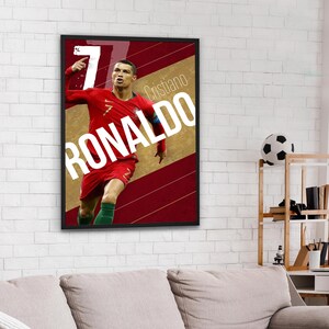 Pu&ograve; includere: Un poster incorniciato con un calciatore che indossa una maglia rossa e verde con il numero 7. Il calciatore &egrave; Cristiano Ronaldo e il poster dice "Cristiano Ronaldo" in lettere bianche.