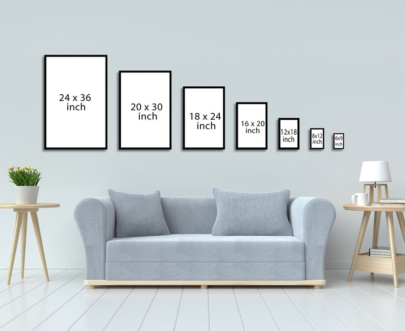 May include: A white wall with a row of black picture frames of different sizes. The frames are empty and have the dimensions listed in inches. A light gray sofa sits in front of the wall. A small table with a lamp and a cup sits on the right side of the image.