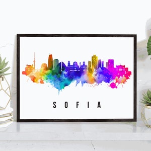 May include: A watercolor painting of the Sofia, Bulgaria skyline with colorful splatter paint accents. The city name "SOFIA" is written in black text below the skyline.