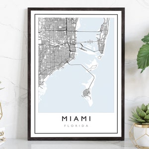 May include: A black and white map of Miami, Florida, with a light blue background. The map shows the city's streets and waterways. The text "MIAMI" and "FLORIDA" is printed below the map.