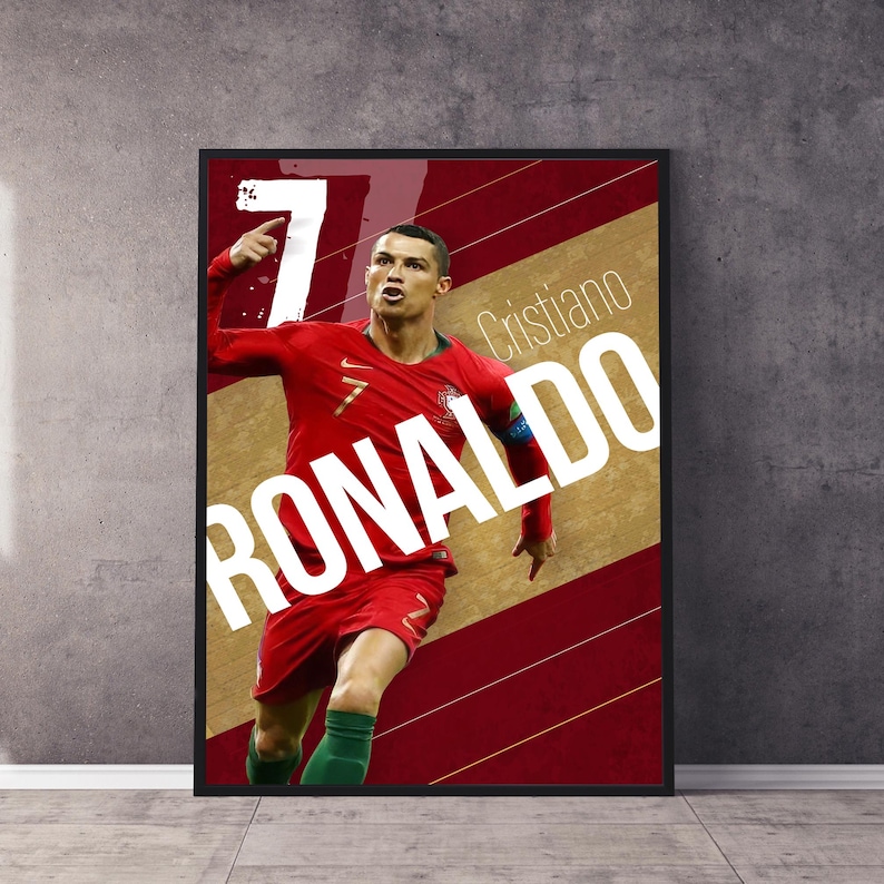 Pu&ograve; includere: Un poster con una foto di Cristiano Ronaldo con una maglia da calcio rossa e verde, che celebra un gol. Il poster ha uno sfondo rosso e oro con il testo "Cristiano Ronaldo" in bianco.