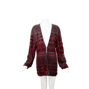 May include: A long-sleeved burgundy cardigan with a geometric pattern of silver sequins. The cardigan has a deep V-neck and a front zipper closure.